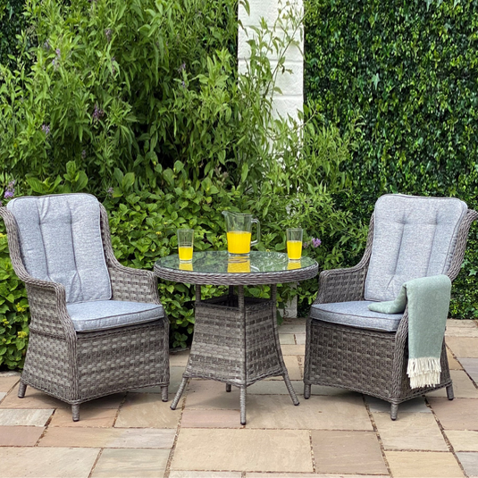 dark grey bistro with round glass topped table and 2 armchairs with cushions