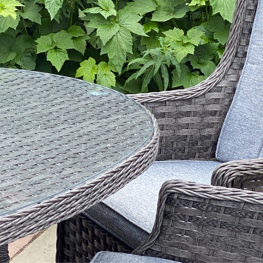 glass topped oval table with dark grey chair and cushions