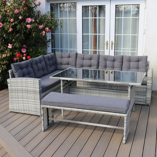 light grey corner sofa set with dark grey cushions, a glass topped rectangular table and 1 bench