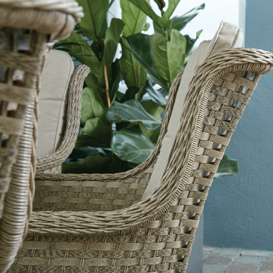 curved armchair in a natural colour with sand coloured back and base cushions